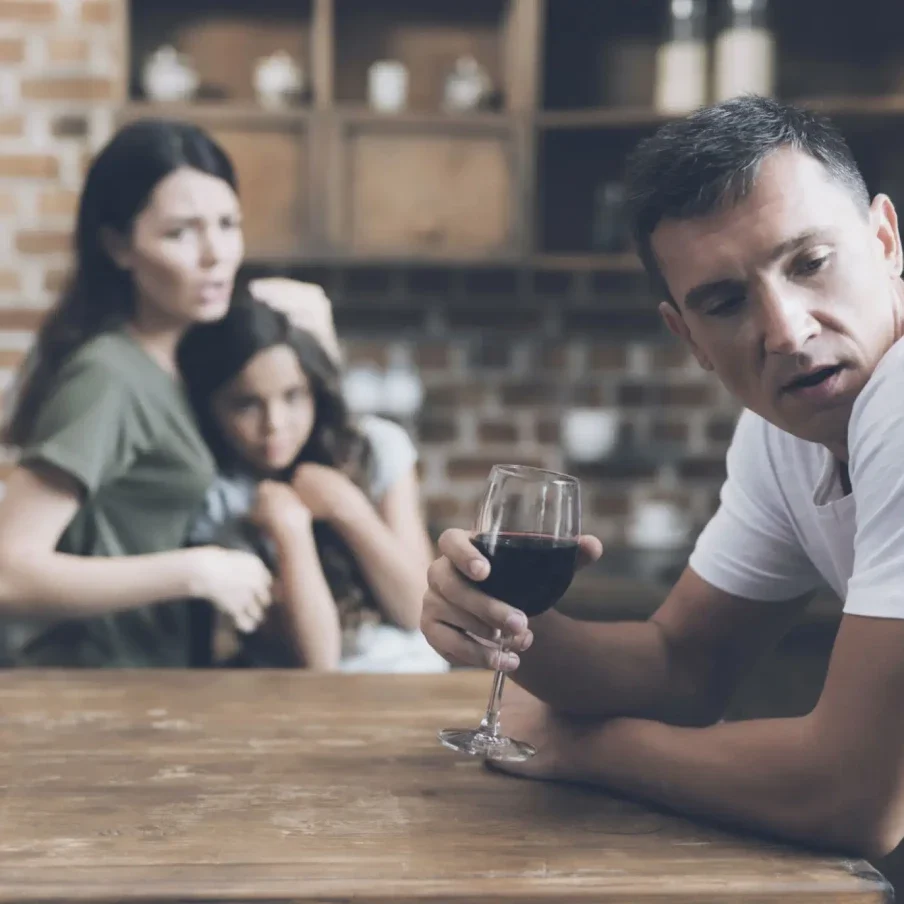 Man drinking wine, family in background