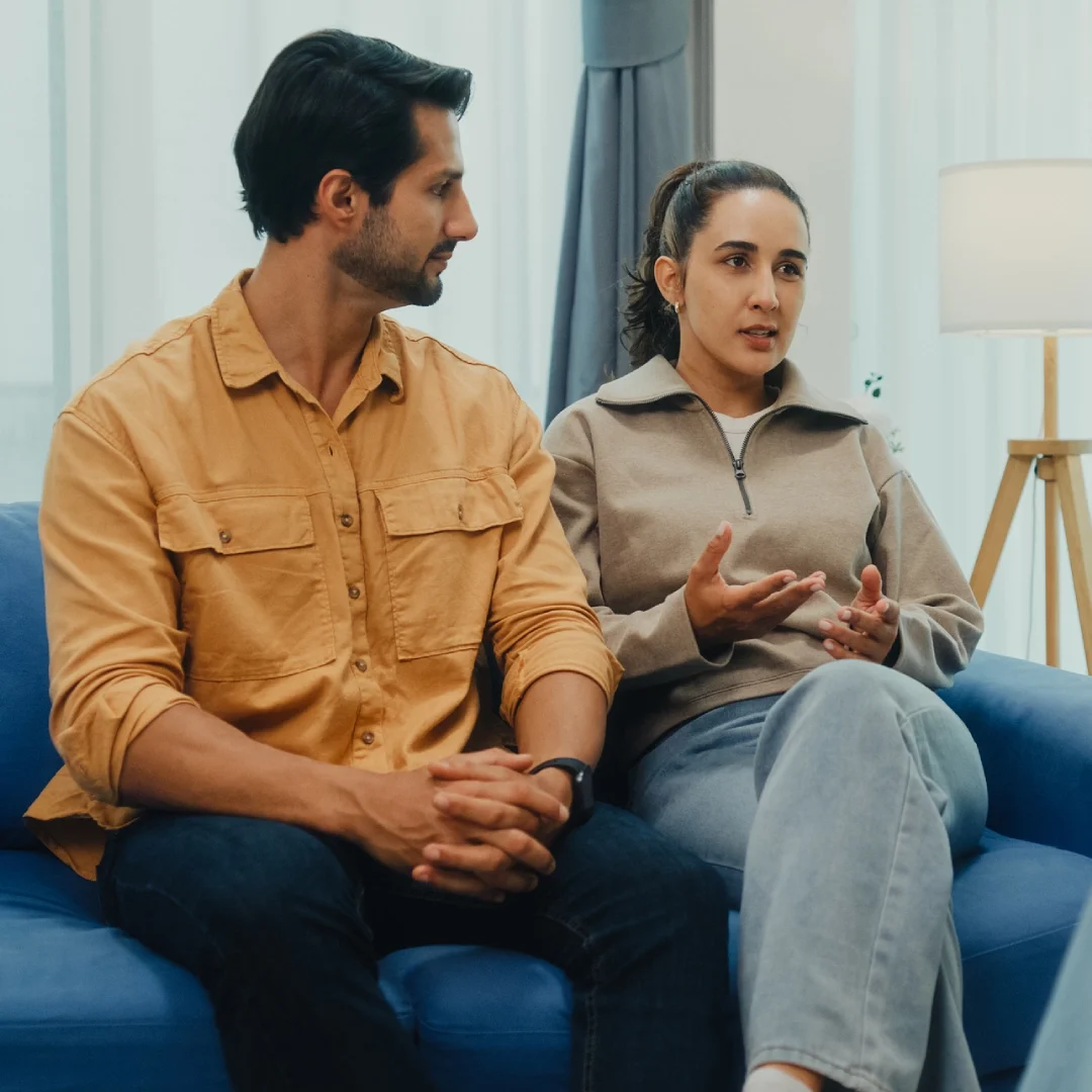 A man and a woman having a serious conversation on a couch.